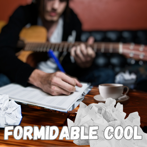 acoustic guitar across his lap. He leans over to write lyrics into a journal on a wooden table. A cup of bergamot tea in a saucer is placed to the side. Crumpled sheet music litters the table foreground.